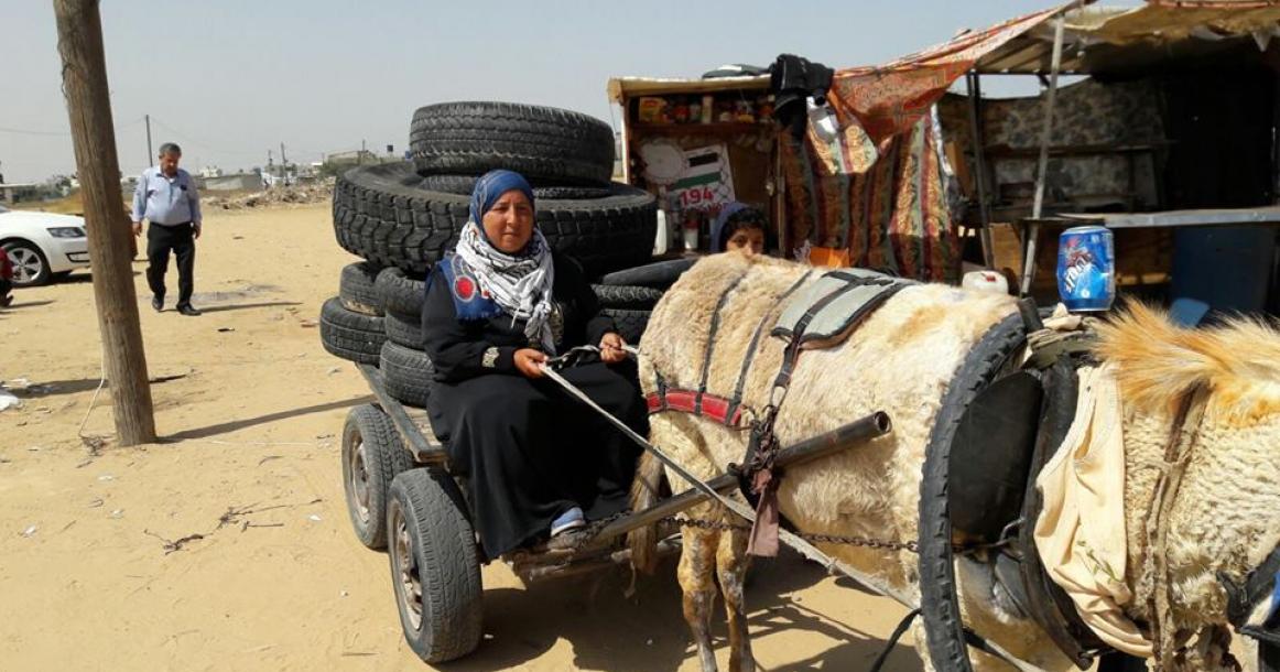 سيدة وطفلها يقومان بجمع الإطارات وإرسالها لمسيرات العودة