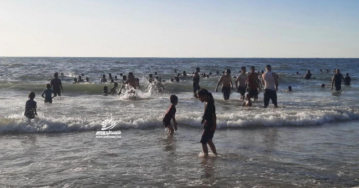 مئات النازحين يجلسون على شاطئ البحر في ظل انقطاع المياه والحر الشديد مع استمرار حرب الإبادة على قطاع غزة