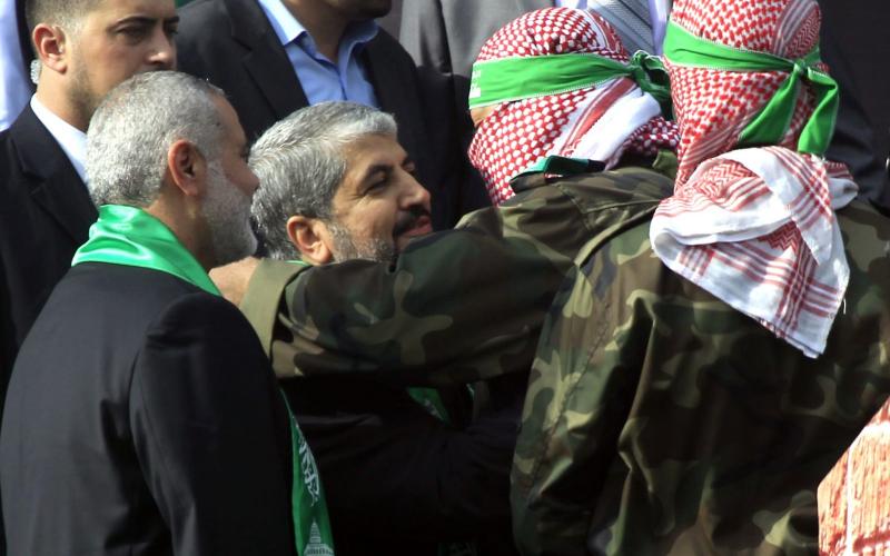 A-Palestinian-member-of-the-Ezzedine-al-Qassam-brigades-hugs-Hamas-chief-Khaled-Meshaal-as-Hamas-prime-minister-Ismail-Haniya-looks