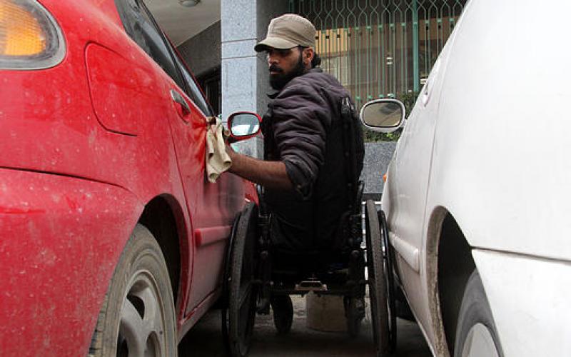 صور.. غزي بلا قدمين يعمل بتنظيف السيارات