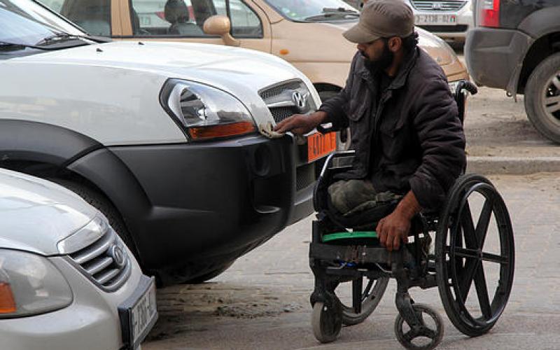 صور.. غزي بلا قدمين يعمل بتنظيف السيارات