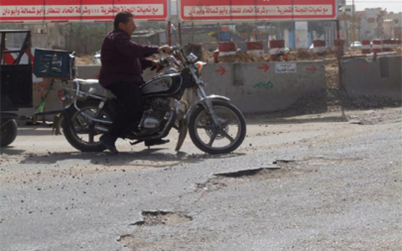 بالصور: حياة السائقين وحفر الموت بشارع صلاح الدين