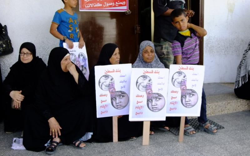 بالصور: أهالي الأيتام يحتجون أمام بنك فلسطين بالوسطى