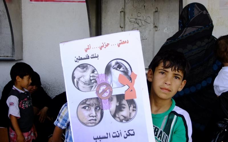 بالصور: أهالي الأيتام يحتجون أمام بنك فلسطين بالوسطى