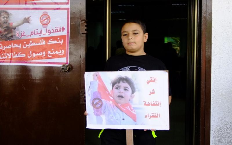 بالصور: أهالي الأيتام يحتجون أمام بنك فلسطين بالوسطى