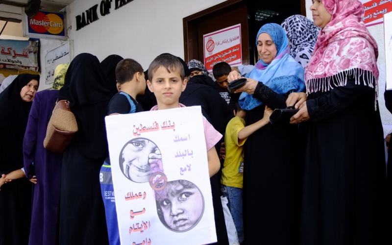 بالصور: أهالي الأيتام يحتجون أمام بنك فلسطين بالوسطى