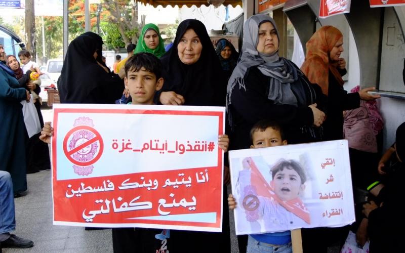بالصور: أهالي الأيتام يحتجون أمام بنك فلسطين بالوسطى