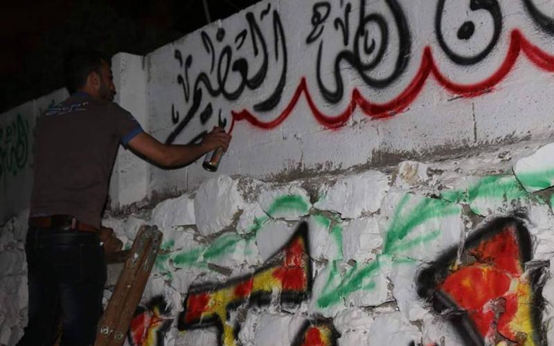 صور: جدران الخليل تتزين بعبارات رمضانية