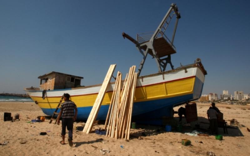 صياد فلسطيني يصلح قاربه على شاطئ غزة