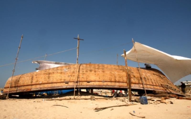 صياد فلسطيني يصلح قاربه على شاطئ غزة
