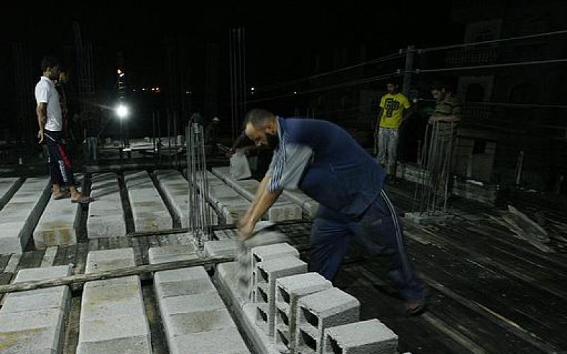 صور.. حرارة النهار تدفع العمال للبناء ليلاً بغزة