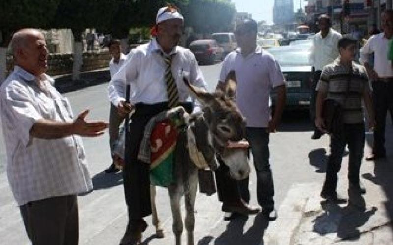 تنديداً بالغلاء.. صحفي يصل نابلس على حمار