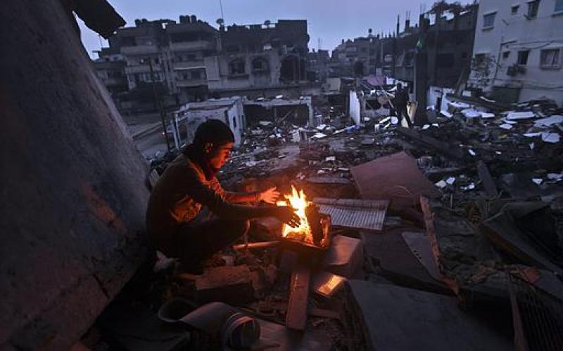 صور.. عائلة فلسطينية تتدفأ قرب منزلها المدمر