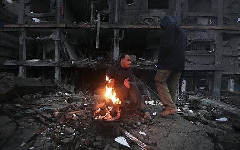 صور.. عائلة فلسطينية تتدفأ قرب منزلها المدمر
