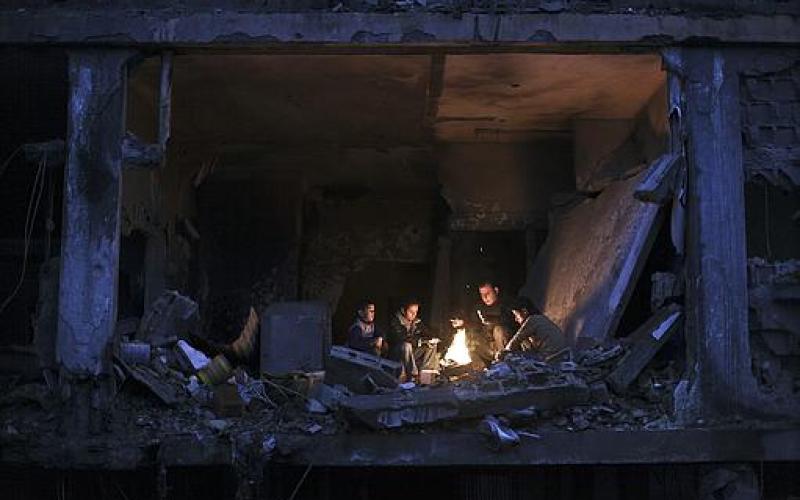 صور.. عائلة فلسطينية تتدفأ قرب منزلها المدمر