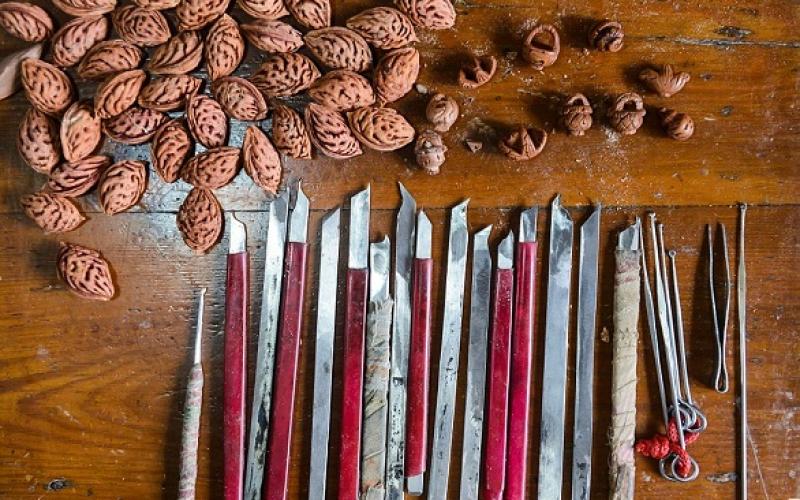 بالصور: فنان صيني متخصص بالنحت على بذور الخوخ